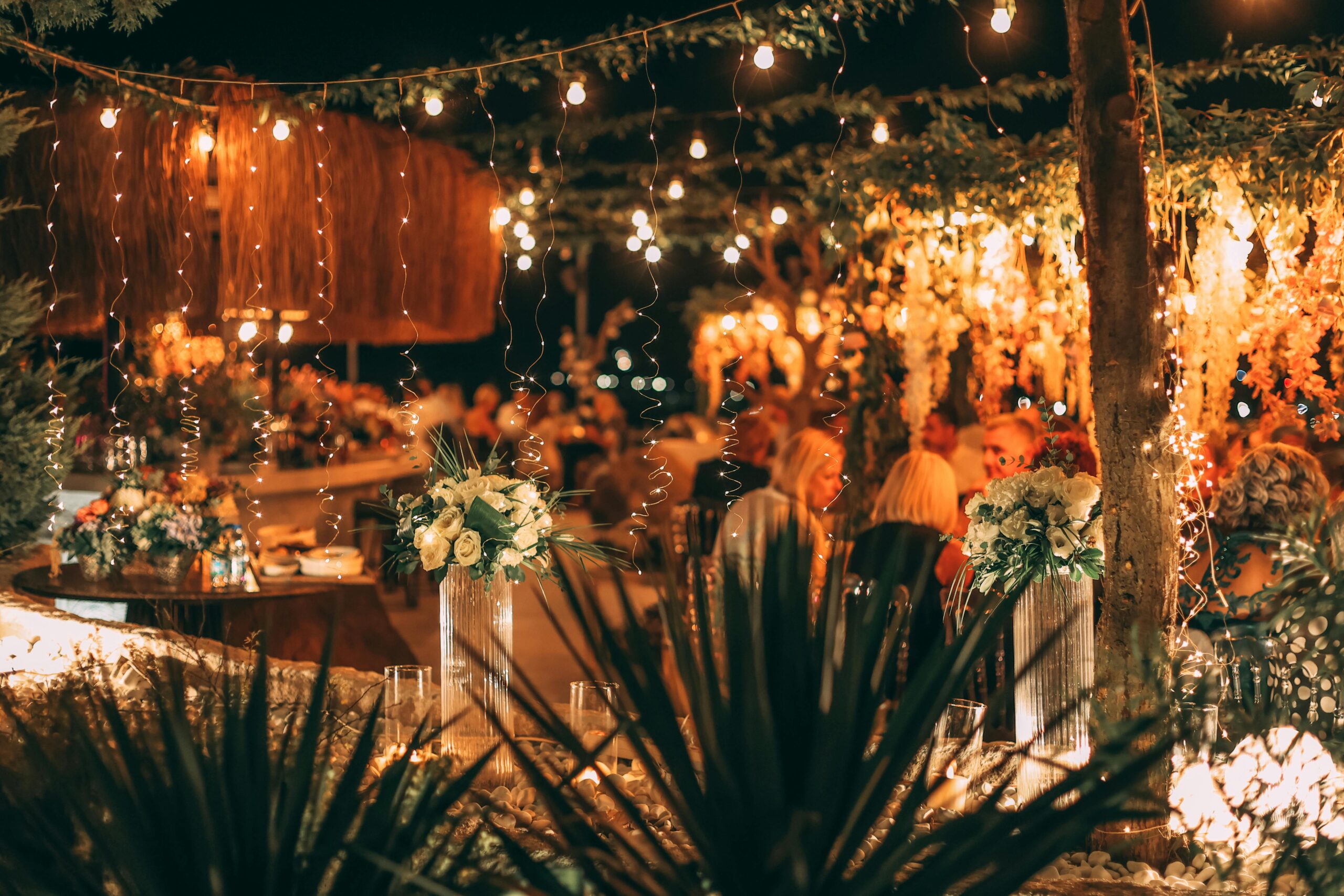 A beautifully lit outdoor setting with hanging lights and floral decor, perfect for social gatherings.