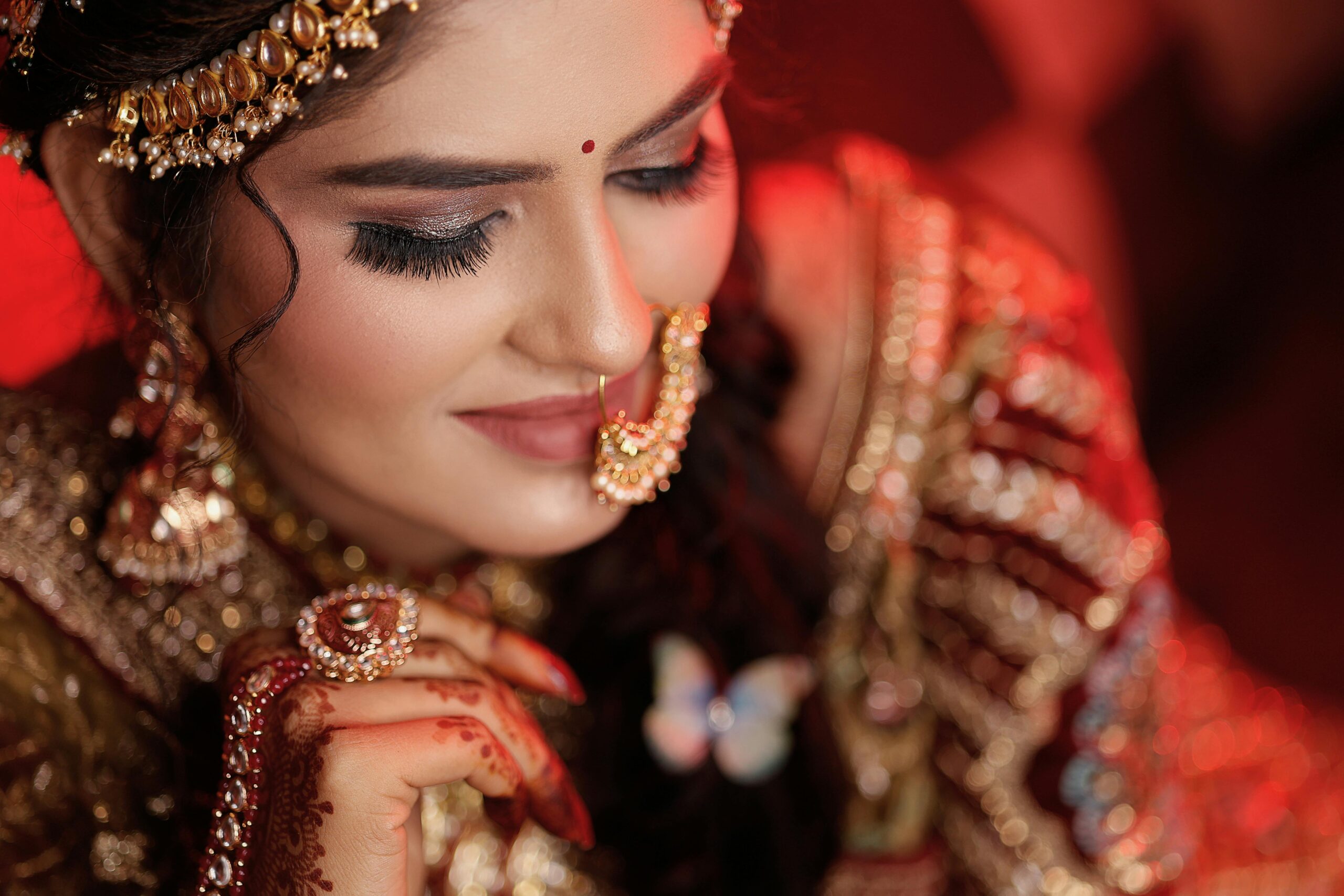 Closeup of a smiling Indian woman with intricate mehendi and ornate jewelry, embodying traditional elegance.